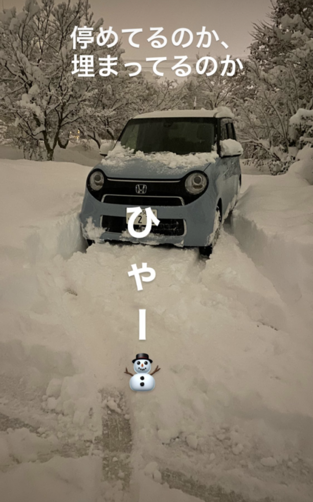 ライトブルー色の車が雪の中に停まっている。「ひゃー」と書いてある。「